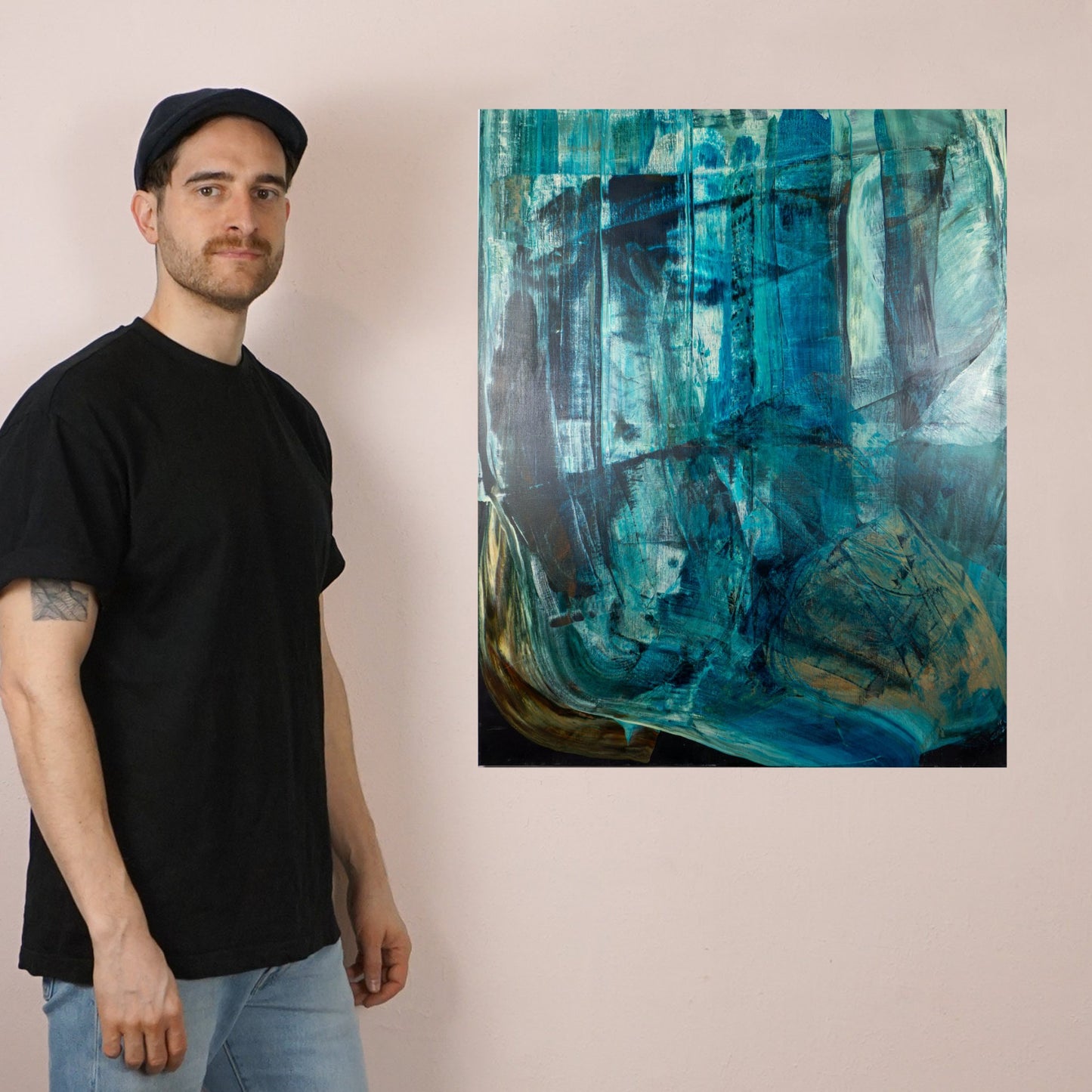 Max Lanzinger standing next to one of his fine art prints with abstract green shapes.