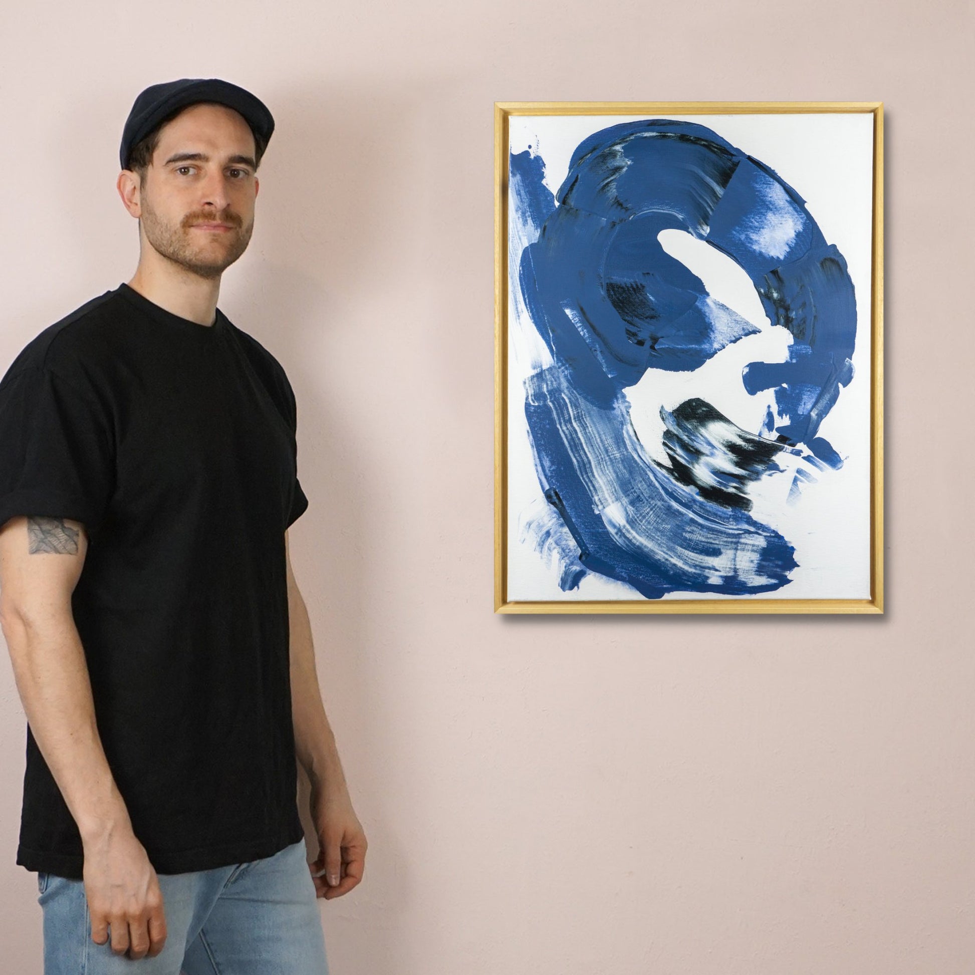Max Lanzinger standing next to one of his original abstract paintings in his art studio.
